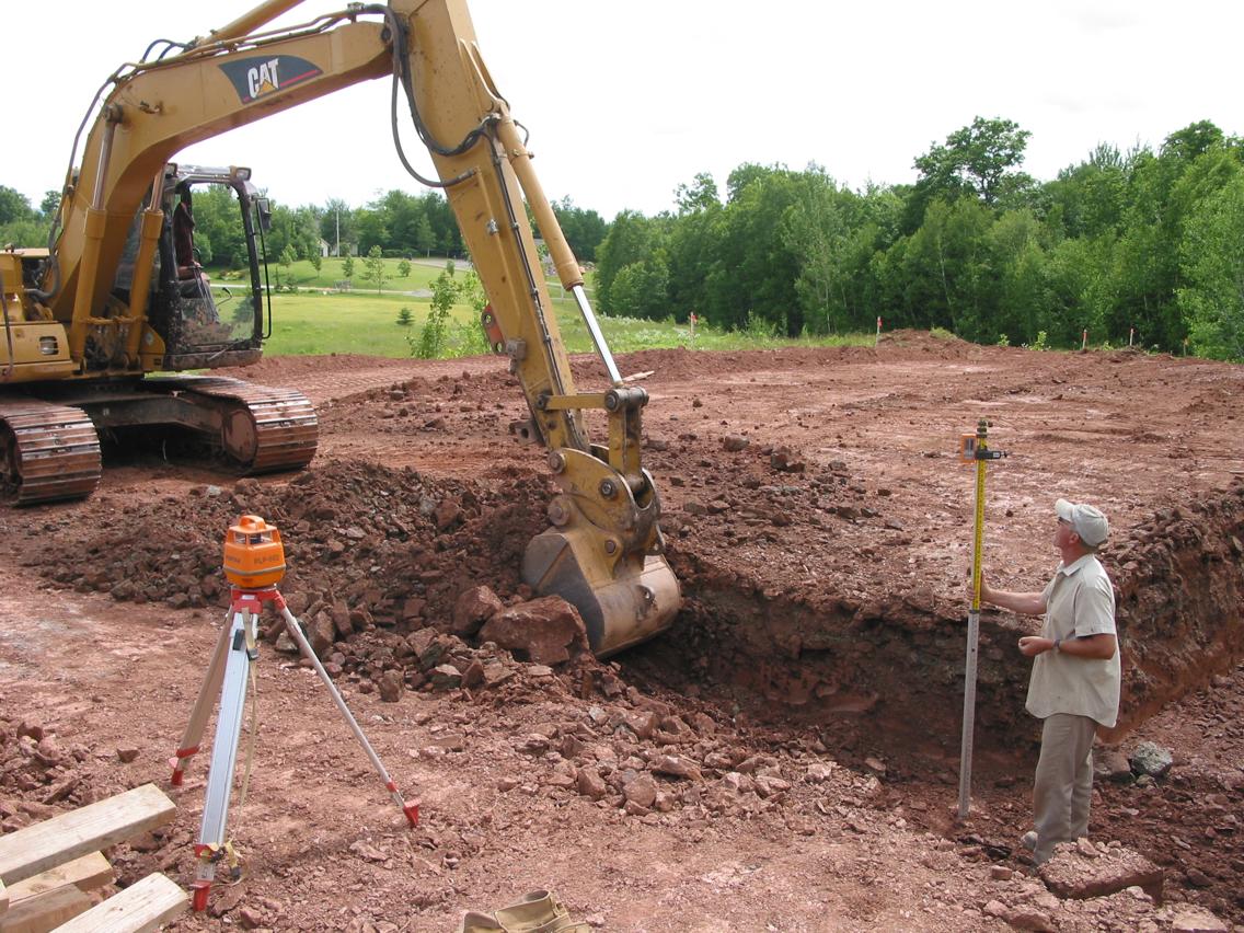Kevin sets the footing depth in the hard pan red clay. Former glacial moraine was 20' above laser level.