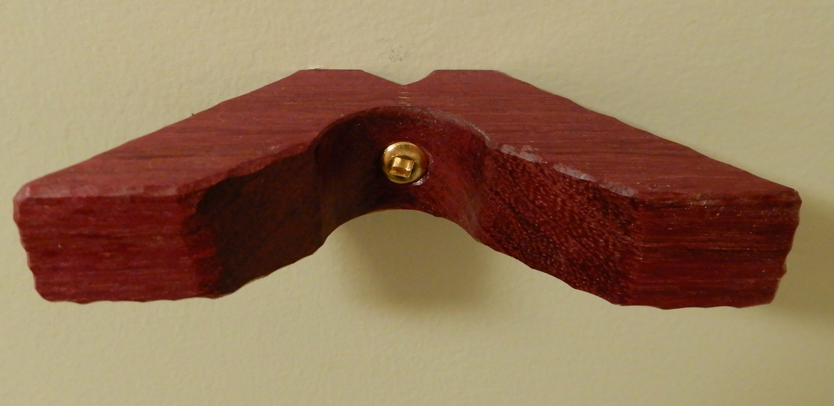 Purpleheart wall bracket affixed by a single gold-plated woodscrew.